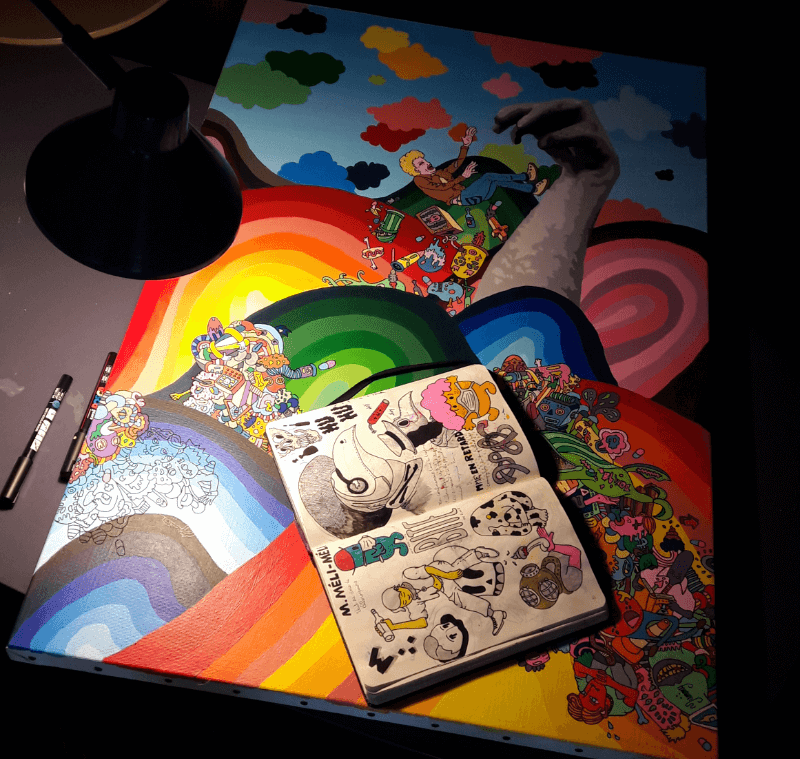 photo d'une toile en cours de réalisation avec le carnet de dessin uvert dessus, exemple du processus de création des oeuvres